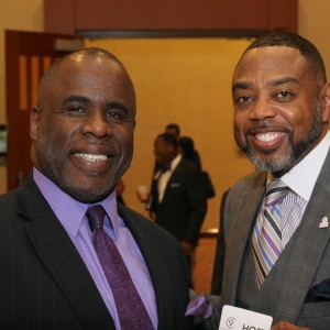 Two gentlemen in suits are standing together and smiling. One of the men is holding a tag with VCIC’s logo.