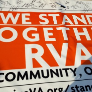 A sign reads “We Stand Together RVA”. People are signing it with a Sharpie visible in the back.